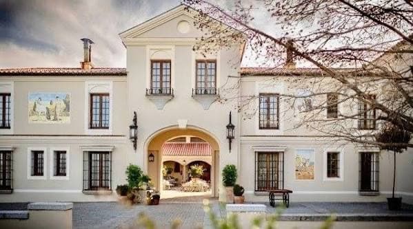 La entrada de La Hacienda: fachada encalada con un gran arco que deja ver el patio interior